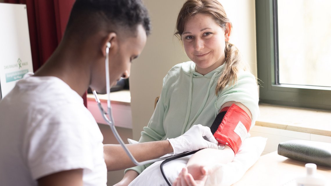 Zwei Pflege-Auszubildende üben Blutdruck messen.